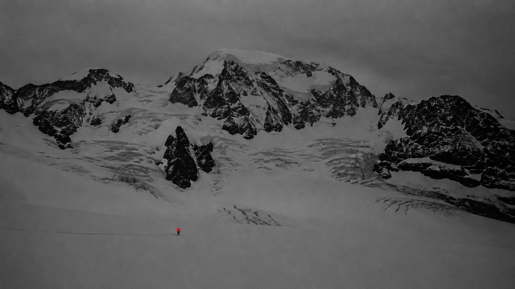 A lone climber crossing a vast Swiss snow massif